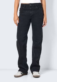 Svart denimjeans med avslappet passform, med rett benkutt, fem lommer og knappeåpning. Båret med nøytrale sko.
