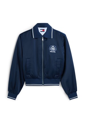 Μπλε σκούρο μπουφάν με φερμουάρ, με λευκή επένδυση στον γιακά, τις μανσέτες και το τελείωμα, που διαθέτει έμβλημα στη δεξιά πλευρά του στήθους και δύο μπροστινές τσέπες.