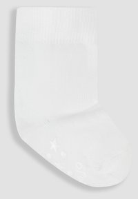 Weißer Baumwollsocken mit gerippter Textur, der eine gepolsterte Sohle mit erhöhten Mustern wie Sterne und Punkte aufweist. Knöchellanges Design.
