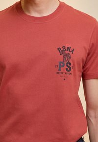 Camiseta de algodón roja con cuello redondo, mangas cortas y un estampado gráfico negro de una cebra con texto en la parte frontal.