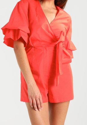 Koralowa sukienka-komplet z obszernymi falbanami na rękawach, przewiązywanym paskiem w talii i gładką fakturą; casualowy fason z szortami.
