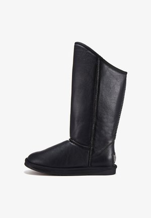 Vysoká černá kožená zimní bota s plochou podrážkou a viditelným šitím, zobrazená v bočním profilu na bílém pozadí.