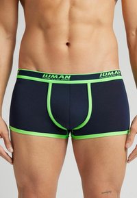 Herrens boxertrosor i mörk marinblått med ljusgröna detaljer. Har en kontrasterande midjeresår och piping; tillverkade av töjbart, mjukt tyg.