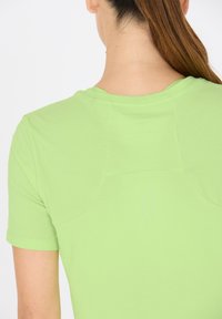 T-paita lyhyillä hihoilla, istuva malli, valmistettu vaaleanvihreästä kankaasta, jossa on pyöreä pääntie ja hienovarainen tekstuuridetaljointi takana.