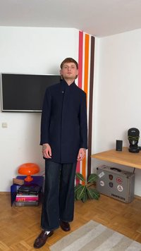 Navy long coat with a high collar and single button closure, paired with wide-leg dark jeans and dark clogs. Smooth fabric, clean lines.