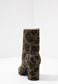 Kotníkové boty s leopardím vzorem v tmavě hnědé barvě na olivově zeleném pozadí. Hladký povrch se širokým podpatkem a uzavřeným designem.