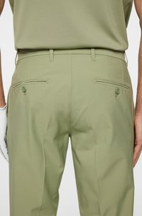 Olivgröna byxor med en slät textur, utrustade med två bakfickor med knappar och en skräddarsydd passform; minimalistisk design.