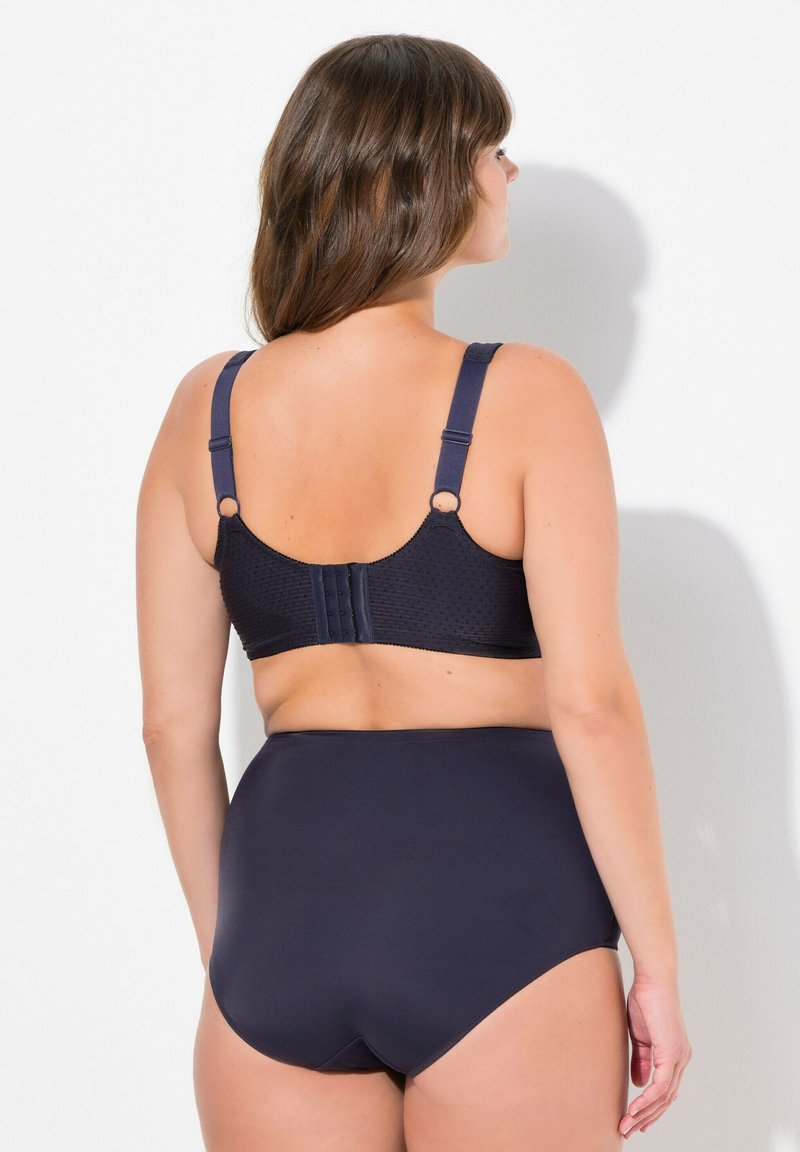 Ensemble de soutien-gorge bleu marine et de culotte taille haute; le soutien-gorge présente un motif texturé et des bretelles réglables, la culotte a une finition lisse et une couverture intégrale.