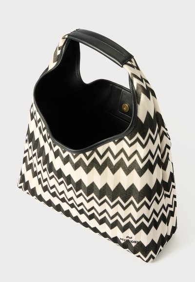 Canvas handbag with black and white zigzag pattern, wide opening, sturdy black handle, and smooth interior. Gold hardware detail present.