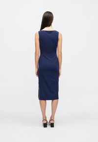 Μπλε ναυτικό φορεμα χωρίς μανίκια με εφαρμοστή σιλουέτα, μήκος μέχρι το γόνατο και αντίθετη πλαϊνή λεπτομέρεια. Λείο υφή και δομημένος σχεδιασμός.