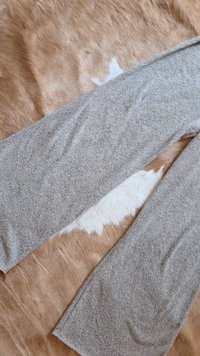 Šedé látkové kalhoty položené na texturovaném hnědém a bílém kožešinovém povrchu, charakterizované měkkou pletenou texturou a tapered (zužujícím se) střihem.