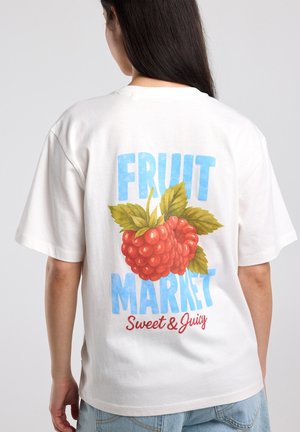 Person trägt ein weißes Hemd mit großem Aufdruck von zwei Himbeeren und dem Text "FRUIT MARKET Sweet & Juicy" auf dem Rücken.