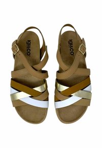 Sandali in pelle tan con cinturini incrociati di un marrone opaco, oro metallico e bianco. Chiusura con fibbia, suola piatta, soletta imbottita.