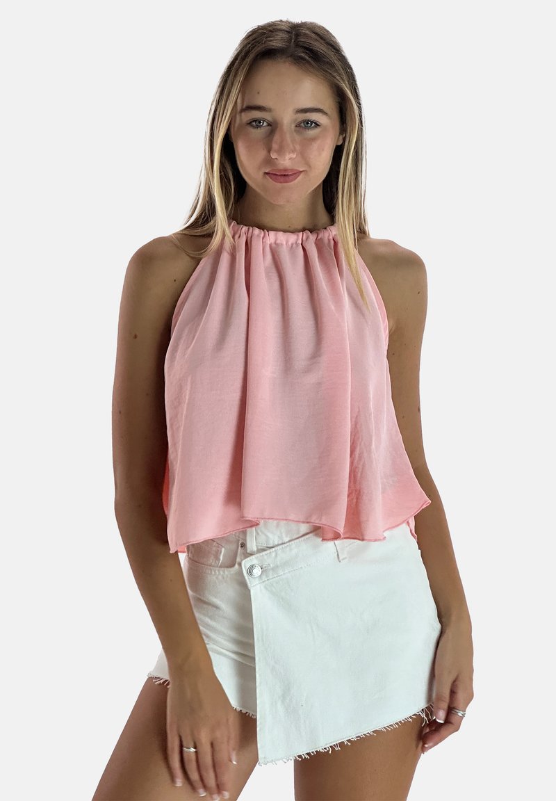 Top rosa tipo halter con escote fruncido, silueta fluida y textura suave, combinado con pantalones cortos de mezclilla blancos asimétricos con dobladillo deshilachado.