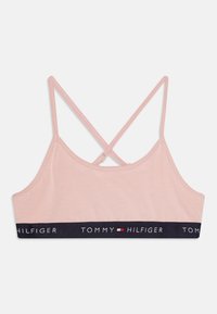 Bralette de color rosa claro con tirantes ajustables y cruzados. Presenta una banda elástica en azul marino con el logotipo "TOMMY HILFIGER" impreso en blanco. Material de algodón suave.