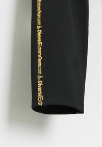 Czarne sportowe szorty o gładkiej fakturze, z bocznym szwem w kolorze złotym z napisem „DiversExtremeTeam.com”. Prosty, funkcjonalny design.