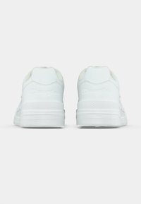 Weiße Sportschuhe mit abgerundeten Rückseiten, strukturierten Gummisohlen und geprägt eingraviertem Markenzeichen an der Ferse. Glattes Lederobermaterial mit kontrastierenden Akzenten.