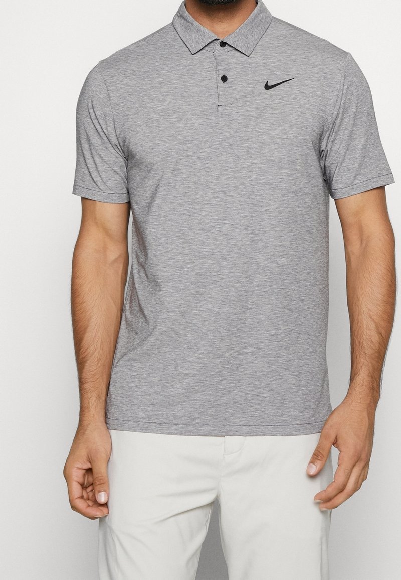 Graues Polo-Shirt mit Kragen, kurzen Ärmeln und schwarzem Nike-Logo auf der linken Brust; aus leichtem, strukturiertem Gewebe gefertigt.