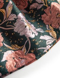 Virágos szövet, amelyen bonyolult rózsaszín és narancssárga virágok találhatók sötétzöld háttéren, arany díszítéssel és mintás, texturált felülettel.