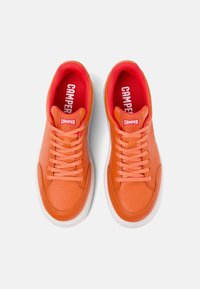 Sneakers in pelle arancione con lacci abbinati e suola in gomma bianca. L'interno presenta un rivestimento rosso brillante e il logo “CAMPER” ben visibile.