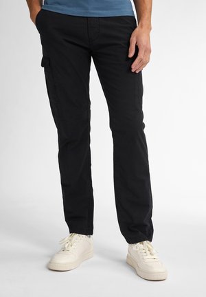 Pantalons cargo noirs avec poches latérales, coupe droite, en coton, associés à des baskets blanches, modèle portant une chemise bleue, fond neutre.