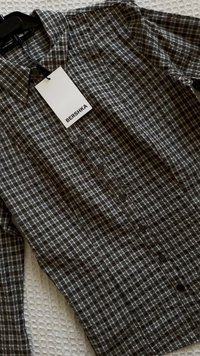 Grau-schwarzes kariertes Hemd zum Knöpfen aus leichtem Stoff, mit klassischem Kragen und sechs vorderen Knöpfen sowie einem Markenetikett.