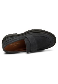 Grå mockapumps med flat sula, med en sydd söm och ett subtilt band över vampen. Inuti har de en brun foder.