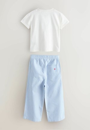 Biela bavlnená tričko s krátkymi rukávmi skombinované so svetlomodrými prúžkovanými nohavicami s elastickým pásom a zadnou vreckom s červeným logom.
