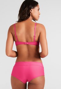 Set di bikini rosa acceso con top a spalline sottili e chiusura regolabile, abbinato a slip a vita alta. Tessuto liscio ed elastico.
