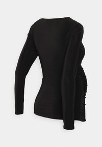 Top preto de mangas longas, feito de um tecido suave e elástico. Apresenta detalhes franzidos nas laterais para uma silhueta ajustada.
