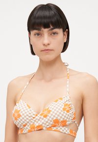 Bikini vrh z karo vzorom v bež in beli barvi, okrašen z oranžnimi cvetličnimi motivi. Zavezuje se okoli vratu z nastavljivimi trakovi.