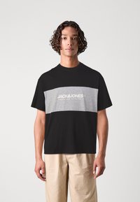 Zwart en grijs kleurblok t-shirt met een ronde halslijn en het "JACK & JONES" logo gedrukt op de voorkant. Zacht katoenen stof, losse pasvorm.
