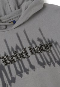Grijze hoodie met "Rebel baby" in vet zwart borduurwerk, voorzien van een gestructureerde afwerking en een subtiel schaduwprintpatroon.