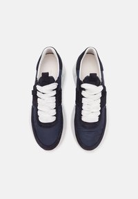 Granatowe sneakersy z gładkim tekstylnym wierzchem, białymi grubymi sznurowadłami i kontrastującą białą gumową podeszwą. Posiadają wyściełany kołnierz i elegancki design.