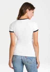 White short-sleeve t-shirt with navy blue ribbed collar, fitted design, smooth texture, and a plain back view. Worn with light blue jeans.