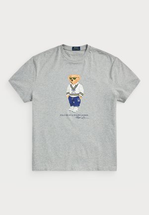 Camiseta de algodón gris con un gráfico de un oso vestido con un traje blanco y azul. "Polo Bear by Ralph Lauren" impreso debajo del diseño.