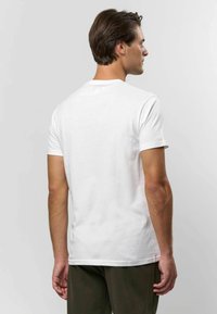 Balta medvilnės marškinėliai su apvalia iškirpte ir trumpomis rankovėmis. Paprastas dizainas, lygus paviršius, prigludusi forma ir jokių matomų raštų ar akcentų.