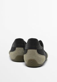 Czarne skórzane buty z pokrytym fakturowanym szarym zamszem obcasem, o zaokrąglonym kształcie i gumowej podeszwie z bieżnikiem. Prosty design, bez ozdób.