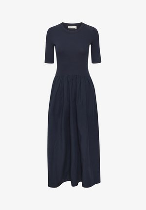 Námořnické šaty se těsným žebrovaným vrškem a splývavou, nařasenou sukní. Krátké rukávy a kulatý výstřih doplňují design.