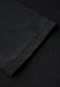 Schwarzer Baumwollstoff mit glatter Textur, ausgestattet mit einem sauber genähten Saum und einem taillierten Design.
