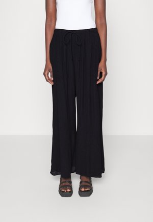 Pantalons larges noirs en tissu léger. Dotés d'une taille élastique avec un cordon de serrage. Texture lisse avec une silhouette fluide.