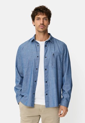 Blue chambray button-up shirt with a collar, long sleeves, and a chest pocket. Material appears textured with a soft finish.