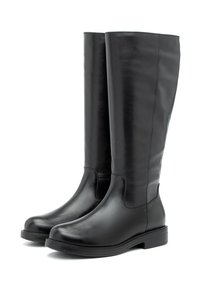 Must beiges, põlve kõrgused mustad nahast saapad madala kontsaga ja ümarate varvastega, esitatud valge tausta ees.