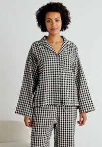 Svart och vitt rutigt mönstrat pyjamas-set med lång ärm, knapp-up skjorta och matchande byxor med elastisk midja.