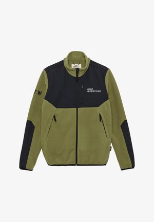 Kurtka polarowa oliwkowa z czarną wzmocnioną łatą materiałową na rękawie i małą metką z tkaniny Cordura blisko kieszeni.