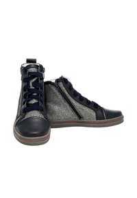 Sneakers alte con una toma metallica argento e dettagli in pelle nera. Presentano lacci blu, cerniera laterale e dettagli in borchie rosse sulla suola.