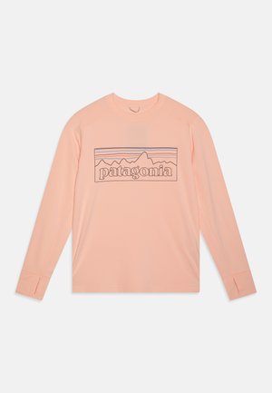 Camisa de manga longa, em pêssego claro, feita de tecido macio, com um gráfico de montanha e o texto "patagonia" em contorno escuro.