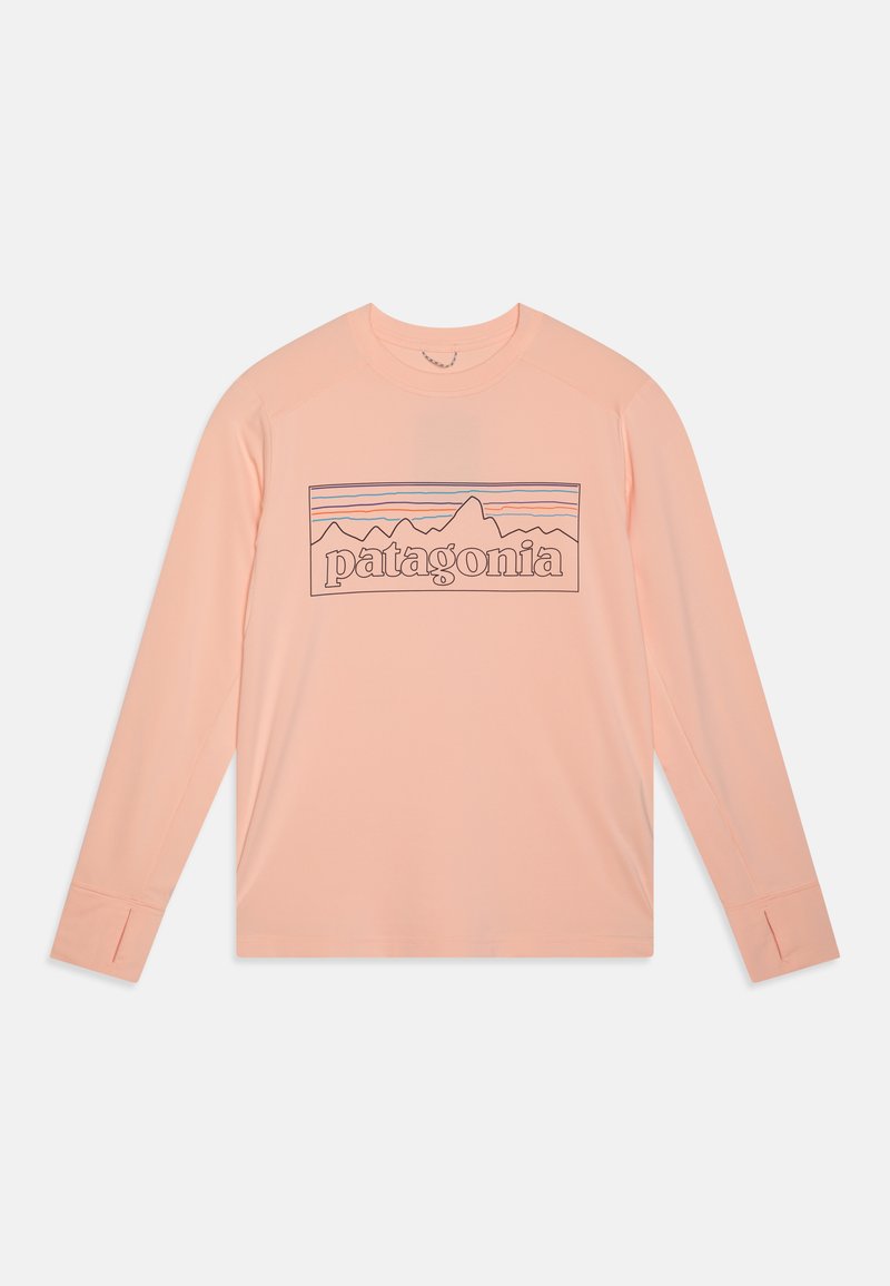 Langermet, lys ferskenfarget skjorte laget av mykt stoff med et fjellmotiv og "patagonia"-tekst i mørk kontur.