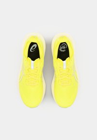 Helle, gelbe Sportschuhe mit einem atmungsaktiven Textil-Obermaterial, Schnürverschluss und einer weichen weißen Zwischensohle. Mit Logo auf den Innensohlen.