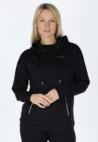 Black hoodie made of soft fabric, featuring a drawstring hood, pockets with zippers, and logo details. Smooth texture, casual fit.